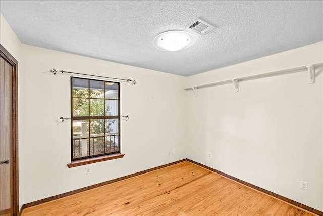 empty room with wood-type flooring and a textured ceiling