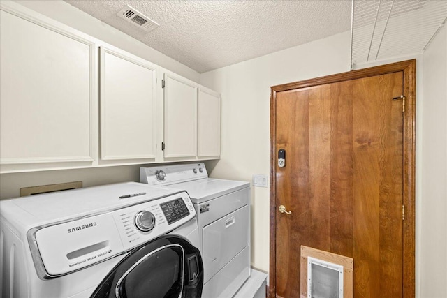 laundry room with cabinets, a textured ceiling, and washing machine and dryer