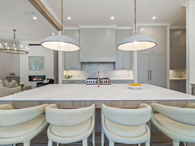 kitchen featuring pendant lighting, crown molding, gray cabinets, a large island, and a breakfast bar area