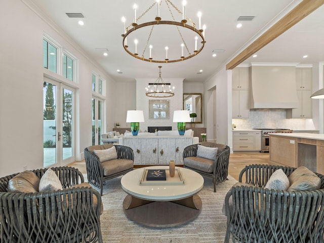 living room with crown molding, french doors, an inviting chandelier, and light wood-type flooring