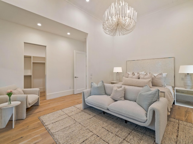 bedroom featuring a walk in closet, crown molding, hardwood / wood-style flooring, an inviting chandelier, and a closet