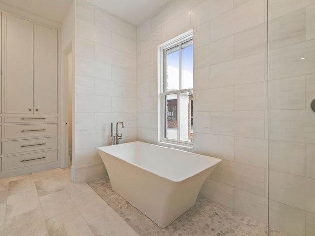 bathroom featuring a bath and tile walls