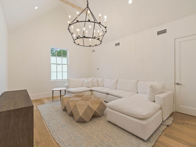 living room with beam ceiling, light wood-type flooring, high vaulted ceiling, and a chandelier