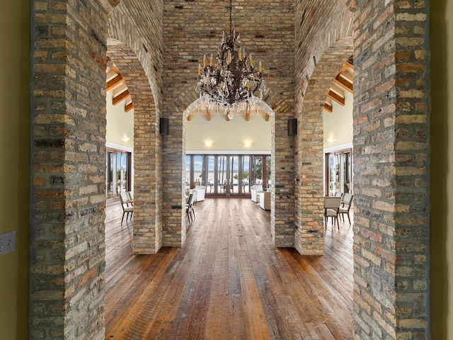 hall featuring beam ceiling, an inviting chandelier, high vaulted ceiling, and hardwood / wood-style flooring