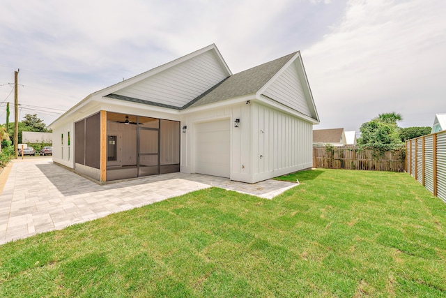 back of property featuring a sunroom, a yard, ceiling fan, a garage, and a patio