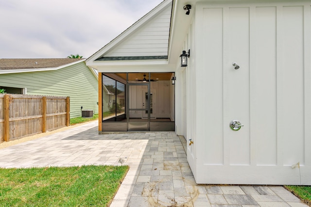 rear view of house with a sunroom, central air condition unit, and a patio