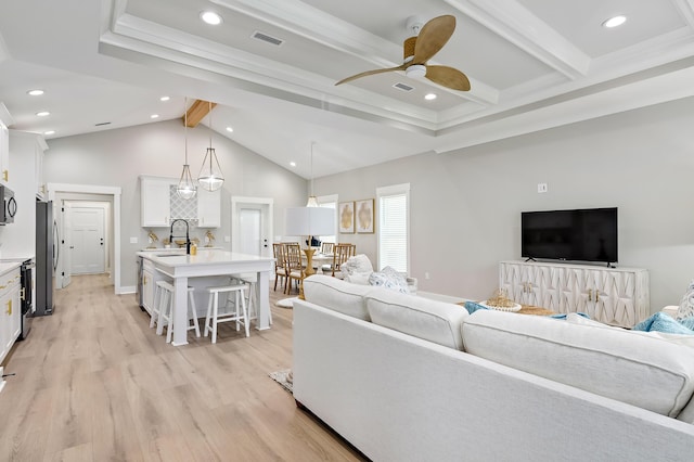 living room featuring vaulted ceiling with beams, light hardwood / wood-style floors, ceiling fan, and sink