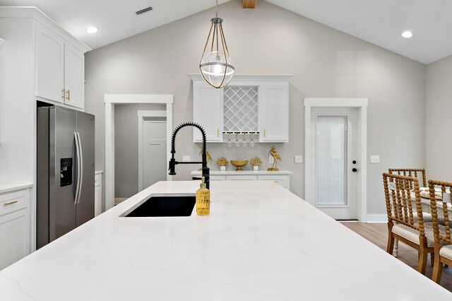 kitchen featuring white cabinetry, sink, stainless steel refrigerator with ice dispenser, pendant lighting, and light wood-type flooring