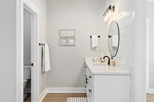 bathroom featuring wood-type flooring, vanity, and toilet