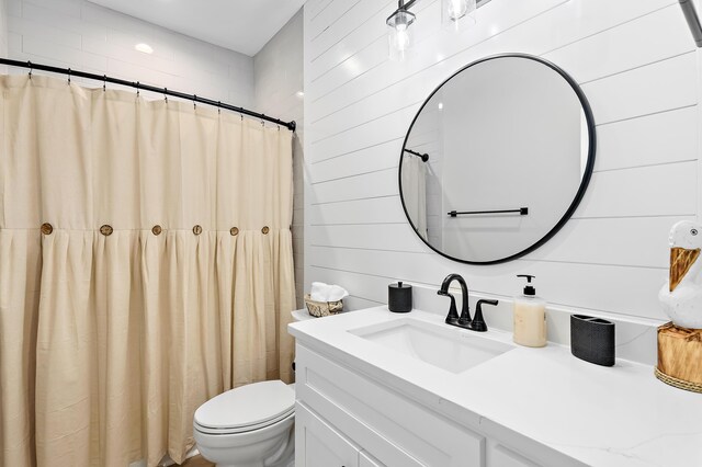 bathroom featuring vanity, toilet, walk in shower, and wood walls