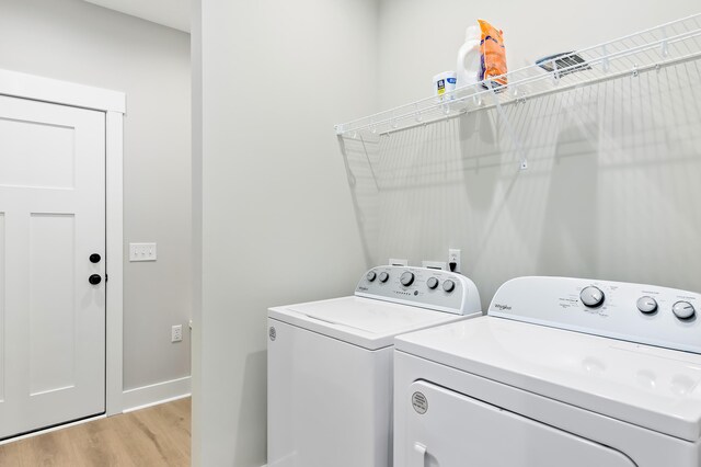 laundry area featuring washing machine and dryer and light hardwood / wood-style flooring