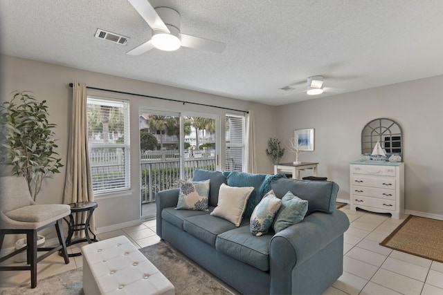 living room with a textured ceiling, ceiling fan, and light tile patterned flooring