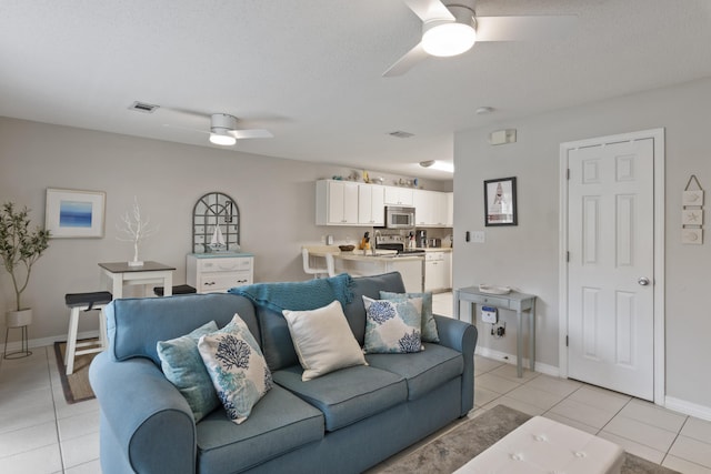 living room featuring a textured ceiling, ceiling fan, and light tile patterned flooring