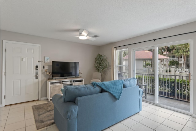 living room featuring light tile patterned floors, a textured ceiling, and ceiling fan