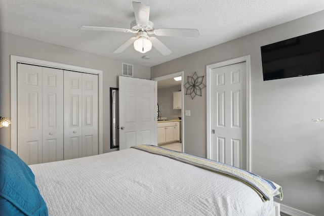 bedroom with ensuite bath, ceiling fan, sink, and a textured ceiling