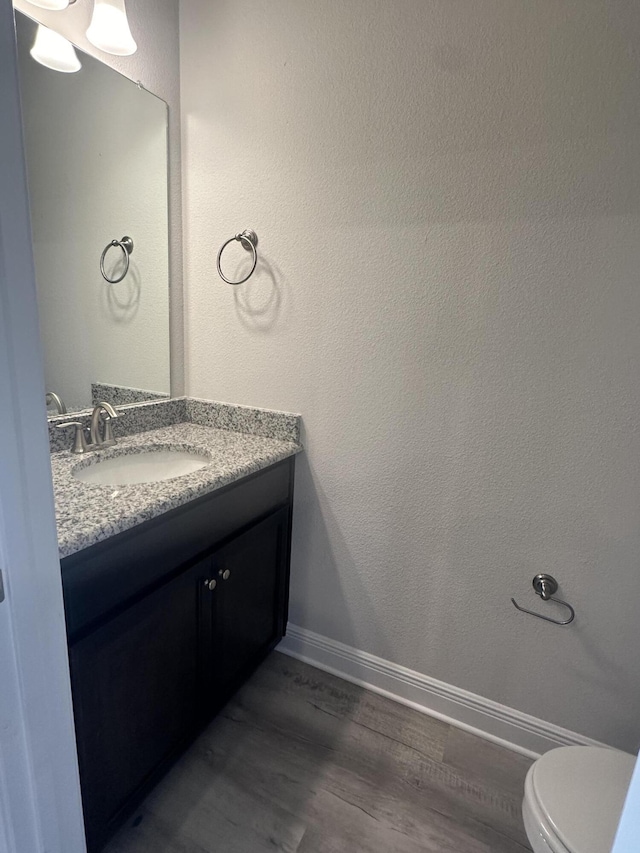 bathroom featuring vanity, wood-type flooring, and toilet