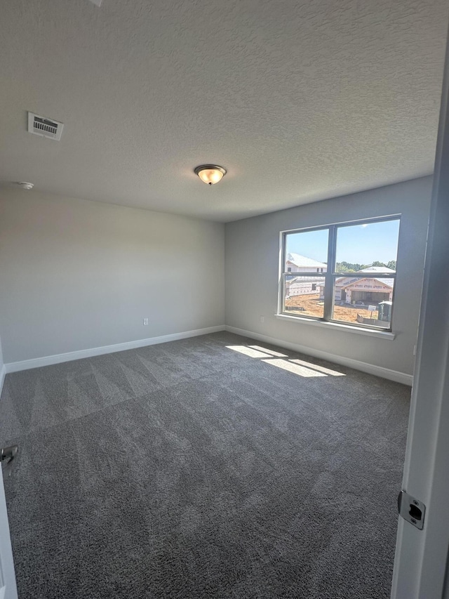 carpeted empty room featuring a textured ceiling