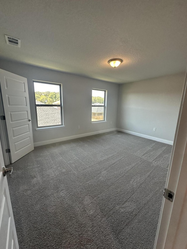 carpeted empty room featuring a textured ceiling