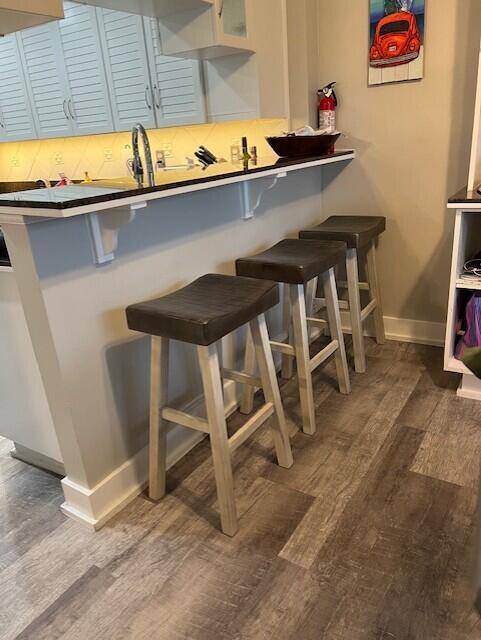 interior space with a kitchen bar, wood-type flooring, and sink