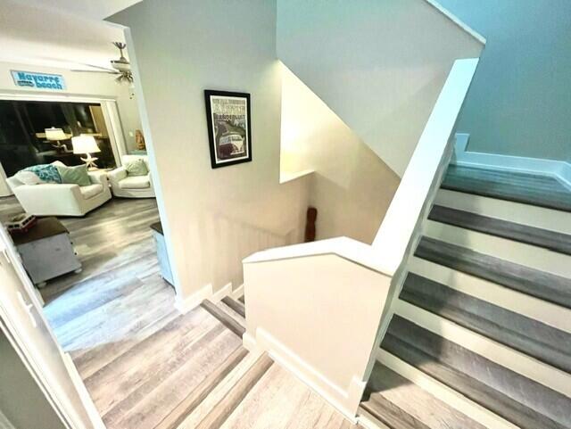 stairway with ceiling fan and wood-type flooring