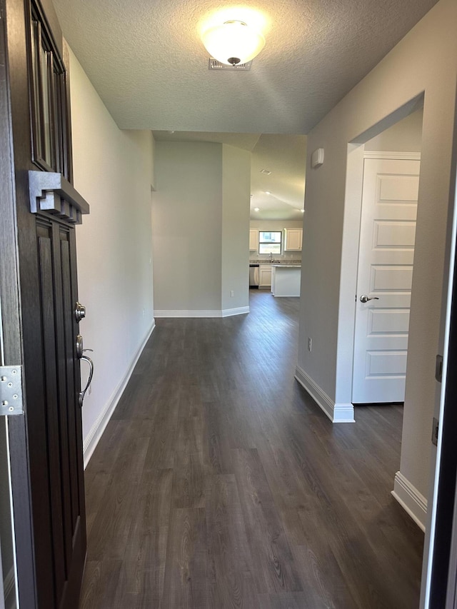 hallway with a textured ceiling and dark wood-type flooring