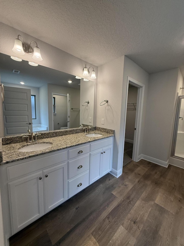 150 Ridgeway Cir, Crestview, FL 32536 - full bath with wood finished floors, double vanity, a textured ceiling, a walk in closet, and a shower stall