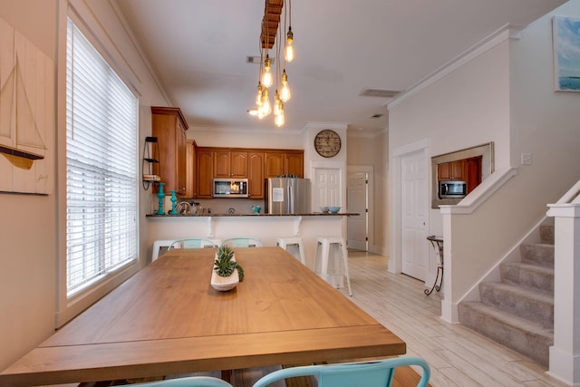 dining room with light wood-type flooring and ornamental molding