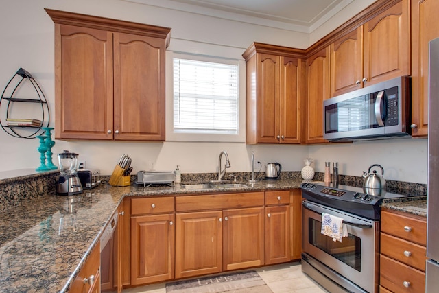 kitchen with dark stone countertops, crown molding, sink, and stainless steel appliances