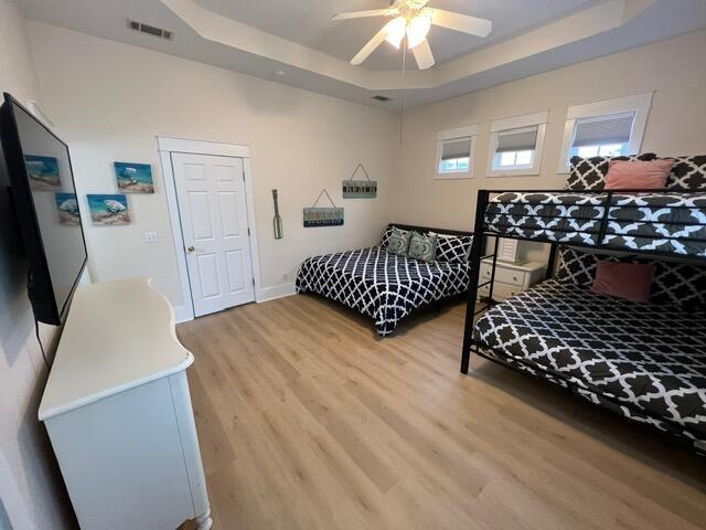 bedroom featuring a raised ceiling, ceiling fan, and wood-type flooring