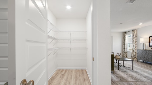 walk in closet with light hardwood / wood-style floors