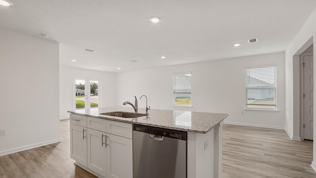 kitchen featuring an island with sink, light stone countertops, stainless steel dishwasher, white cabinets, and sink