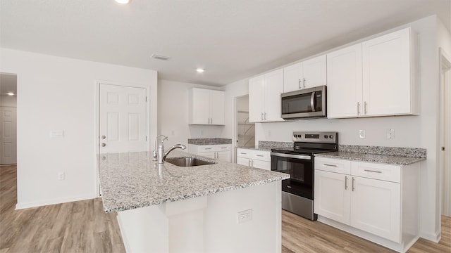 kitchen featuring stainless steel appliances, a kitchen island with sink, white cabinetry, and sink