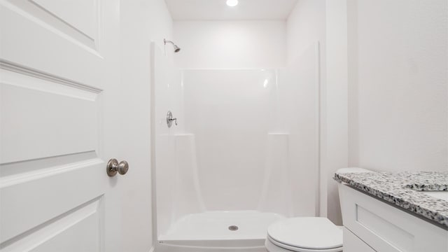 bathroom with toilet, vanity, and a shower