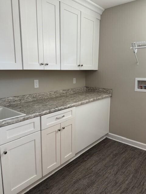 washroom with washer hookup, dark hardwood / wood-style flooring, cabinets, and sink