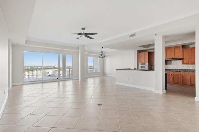 unfurnished living room featuring a tray ceiling, light tile patterned flooring, and ceiling fan with notable chandelier