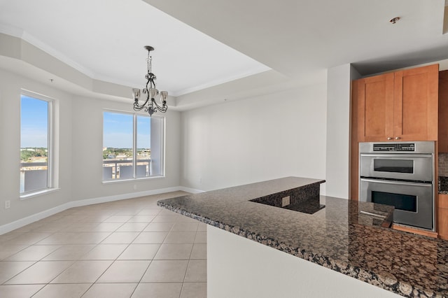 kitchen featuring a notable chandelier, dark stone countertops, ornamental molding, and double oven