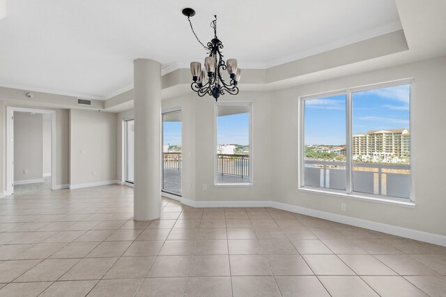 tiled empty room featuring a raised ceiling, crown molding, a wealth of natural light, and an inviting chandelier