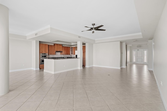 unfurnished living room with a tray ceiling, ceiling fan, and light tile patterned floors