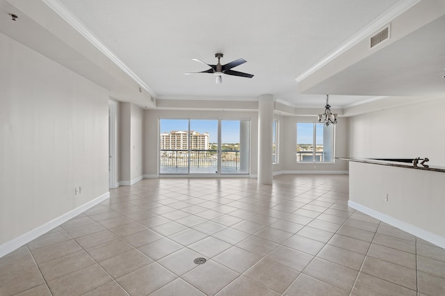 tiled empty room featuring ceiling fan with notable chandelier, a tray ceiling, and ornamental molding