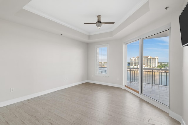 unfurnished room featuring a tray ceiling, ceiling fan, light hardwood / wood-style flooring, and crown molding