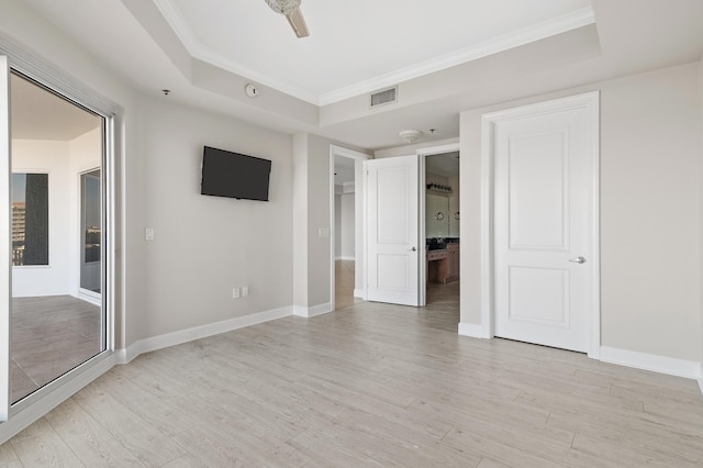 unfurnished room featuring ceiling fan, a raised ceiling, light wood-type flooring, and ornamental molding