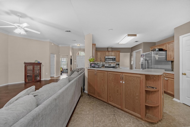 kitchen featuring kitchen peninsula, appliances with stainless steel finishes, ceiling fan, crown molding, and light tile patterned floors