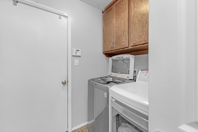 laundry room with cabinets, a textured ceiling, and separate washer and dryer