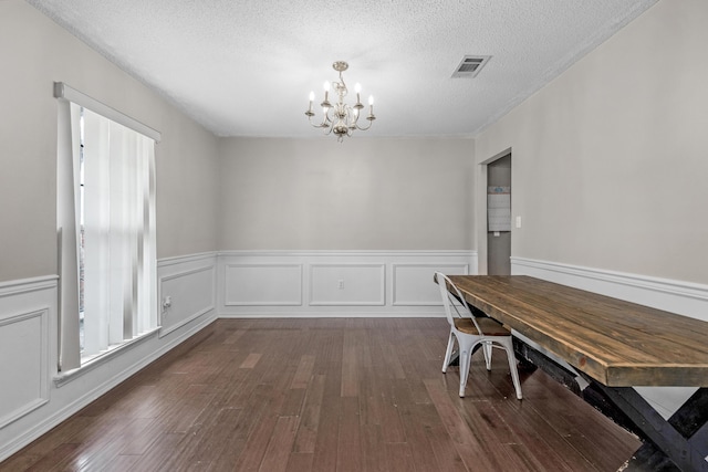 unfurnished dining area featuring a chandelier, a textured ceiling, and dark hardwood / wood-style floors