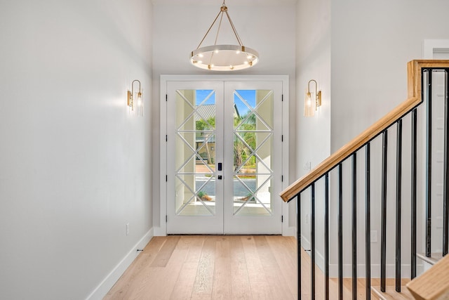 foyer with french doors, light wood-type flooring, and a notable chandelier