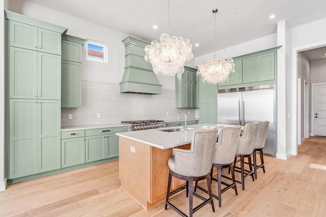 kitchen with light hardwood / wood-style flooring, sink, a kitchen island with sink, and stainless steel appliances