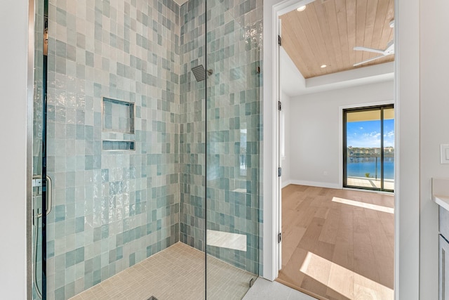 bathroom with wood-type flooring, a water view, and an enclosed shower