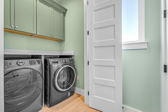 washroom featuring cabinets, separate washer and dryer, and light hardwood / wood-style floors