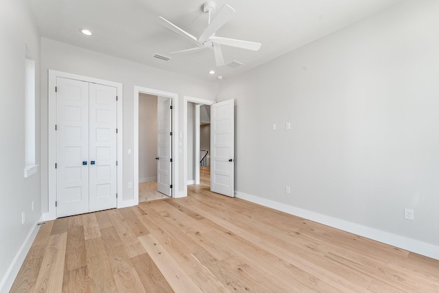 unfurnished bedroom with ceiling fan, a closet, light wood-type flooring, and ensuite bath