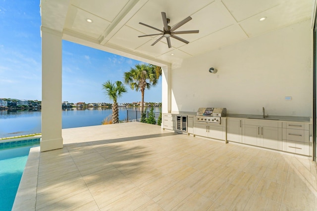 view of patio with sink, exterior kitchen, a water view, grilling area, and wine cooler